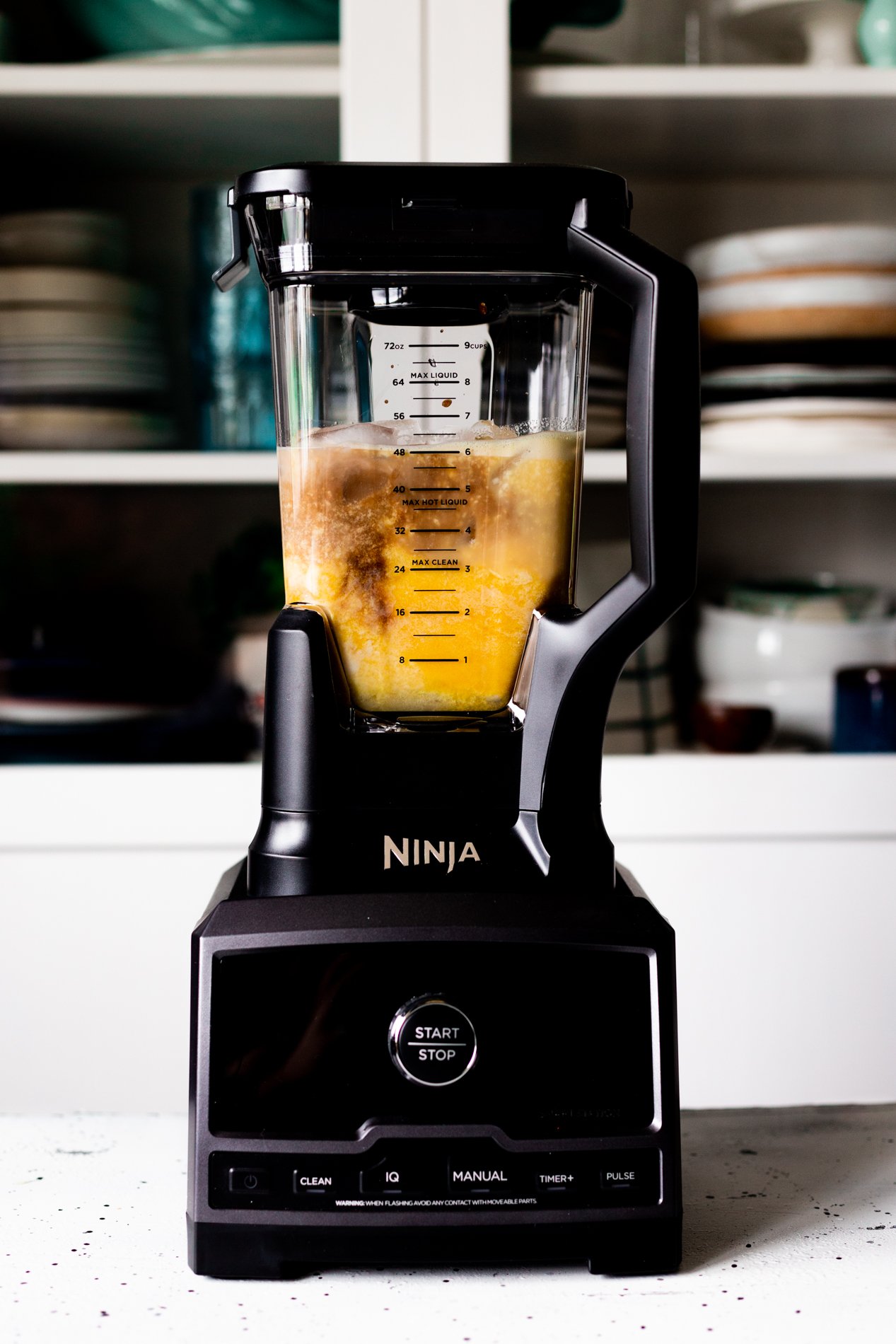 straight forward view of a blender with ingredients for homemade orange julius inside it before blending