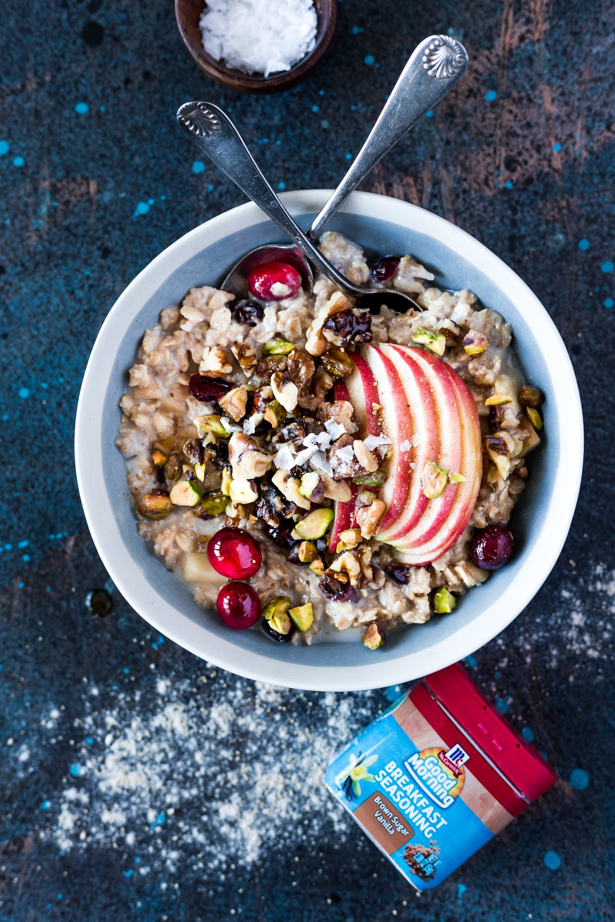 bowl of slow cooker warm apple and cranberry overnight oats topped with sliced apple, pistachios, walnuts, and fresh cranberries
