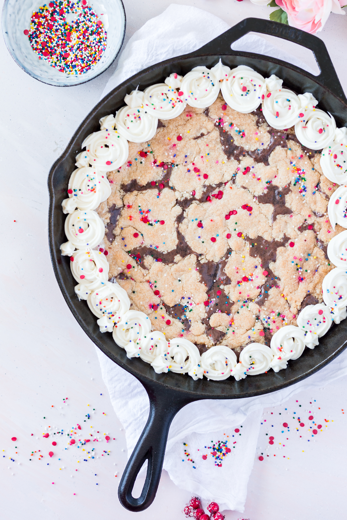 Cast iron skillet brookie with vanilla frosting and funfetti sprinkles.