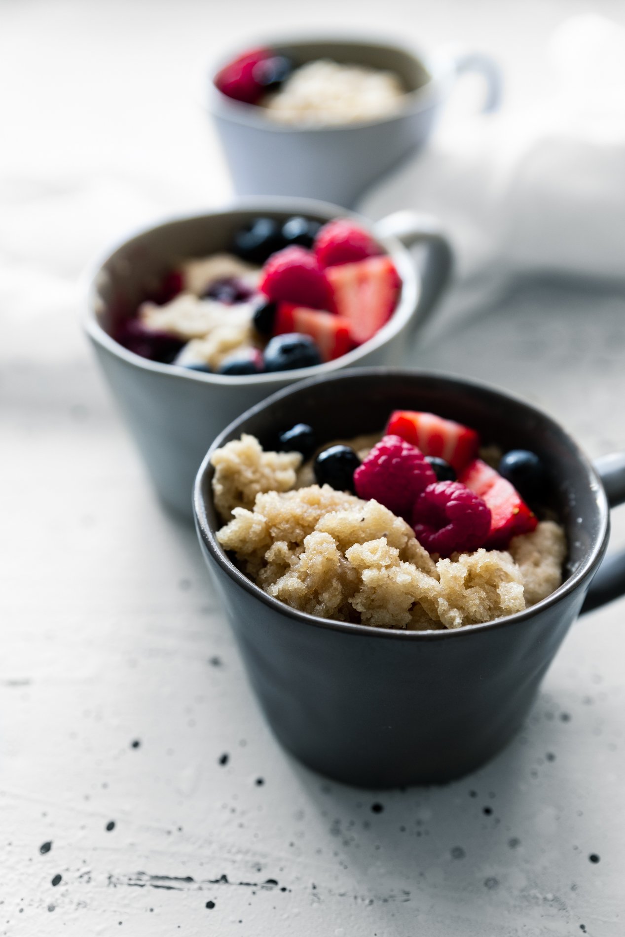 side view of three cups of gluten free mug cake topped with fresh berries