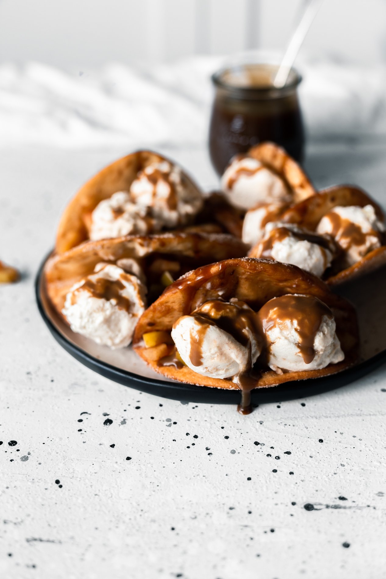 straight forward view of a plate of easy apple crumble dessert tacos with vegan caramel sauce