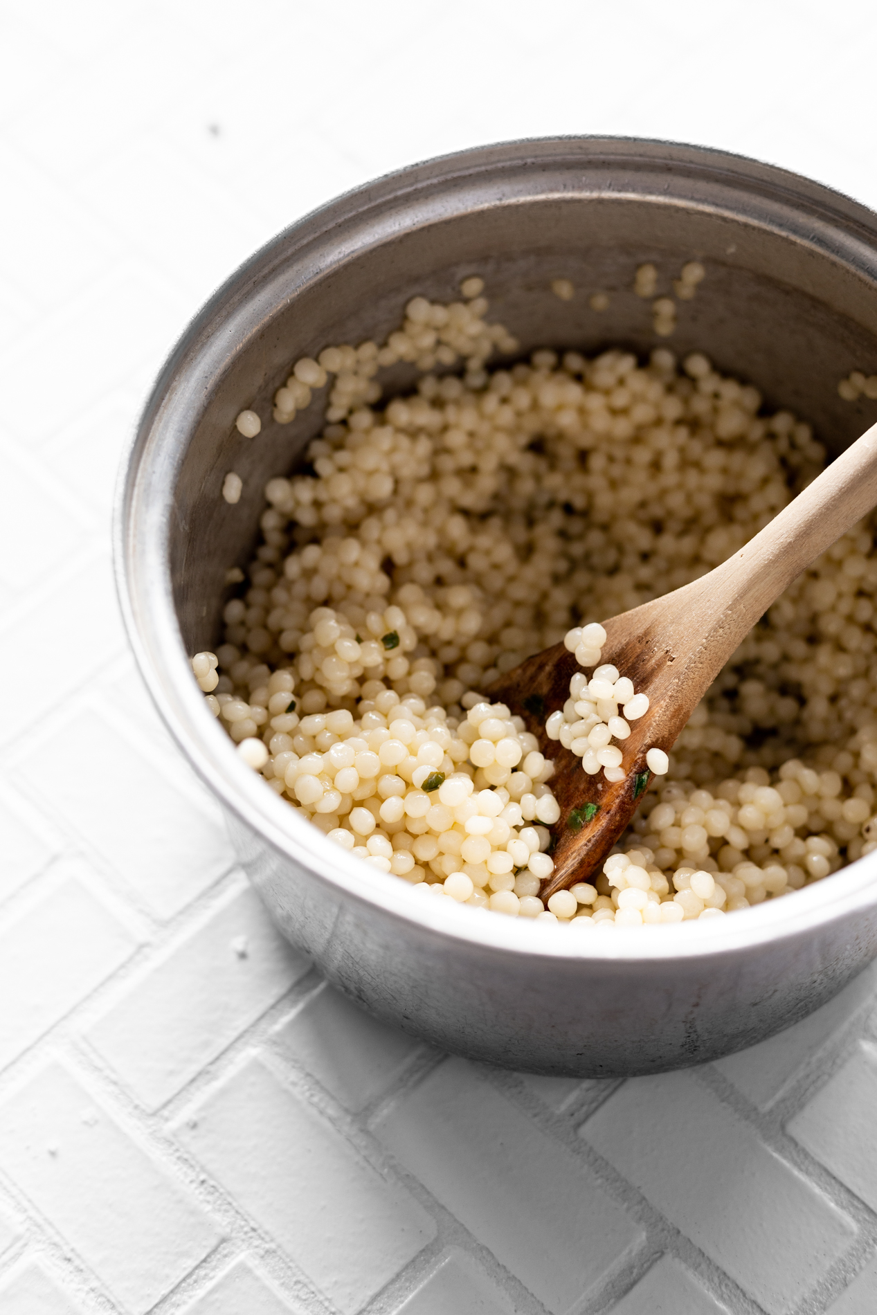 angled view of a pot of cooked couscous coated in lemon basil vinaigrette