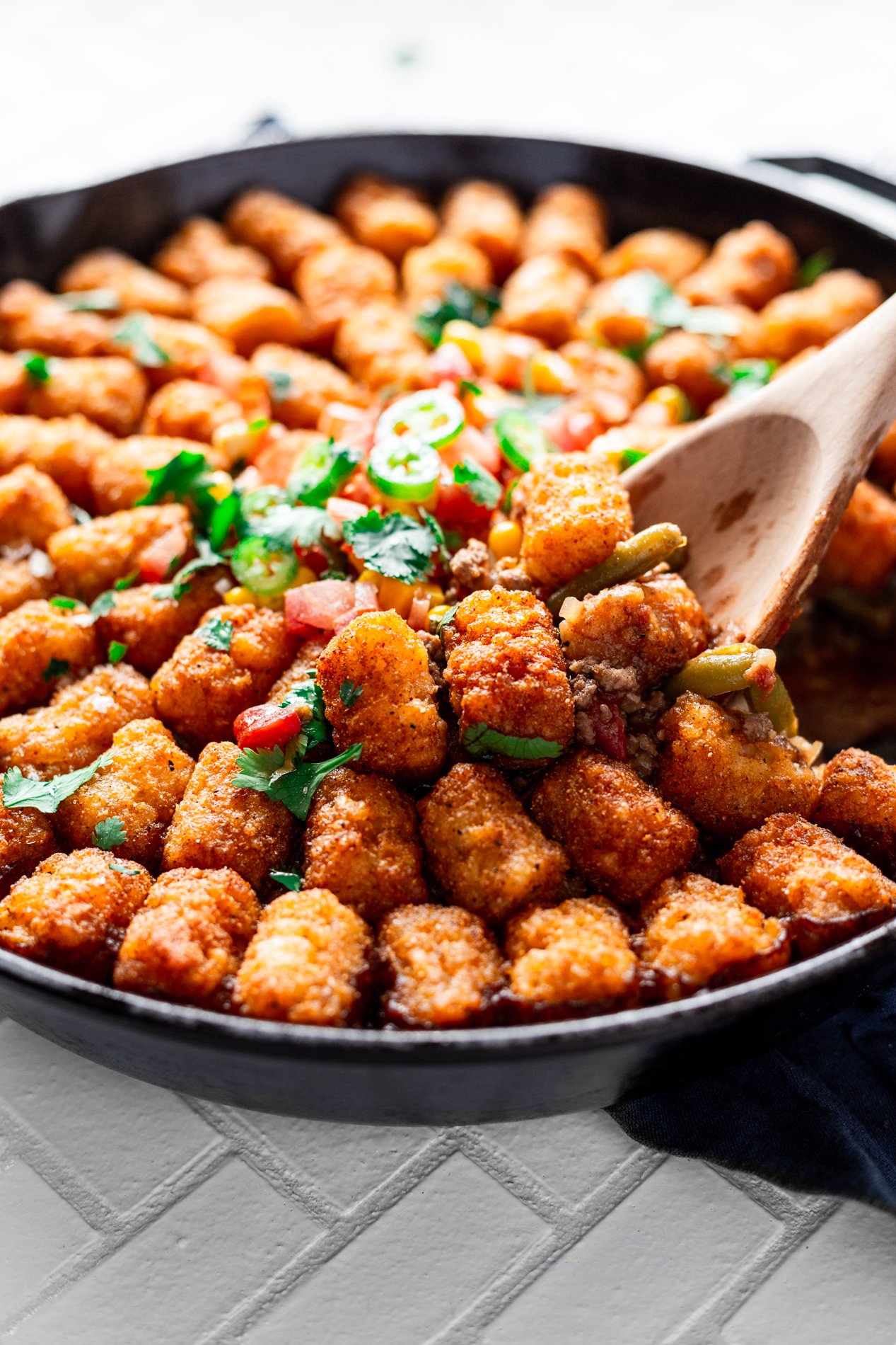 angled view of a scoop of tater tot hotdish being pulled from a skillet