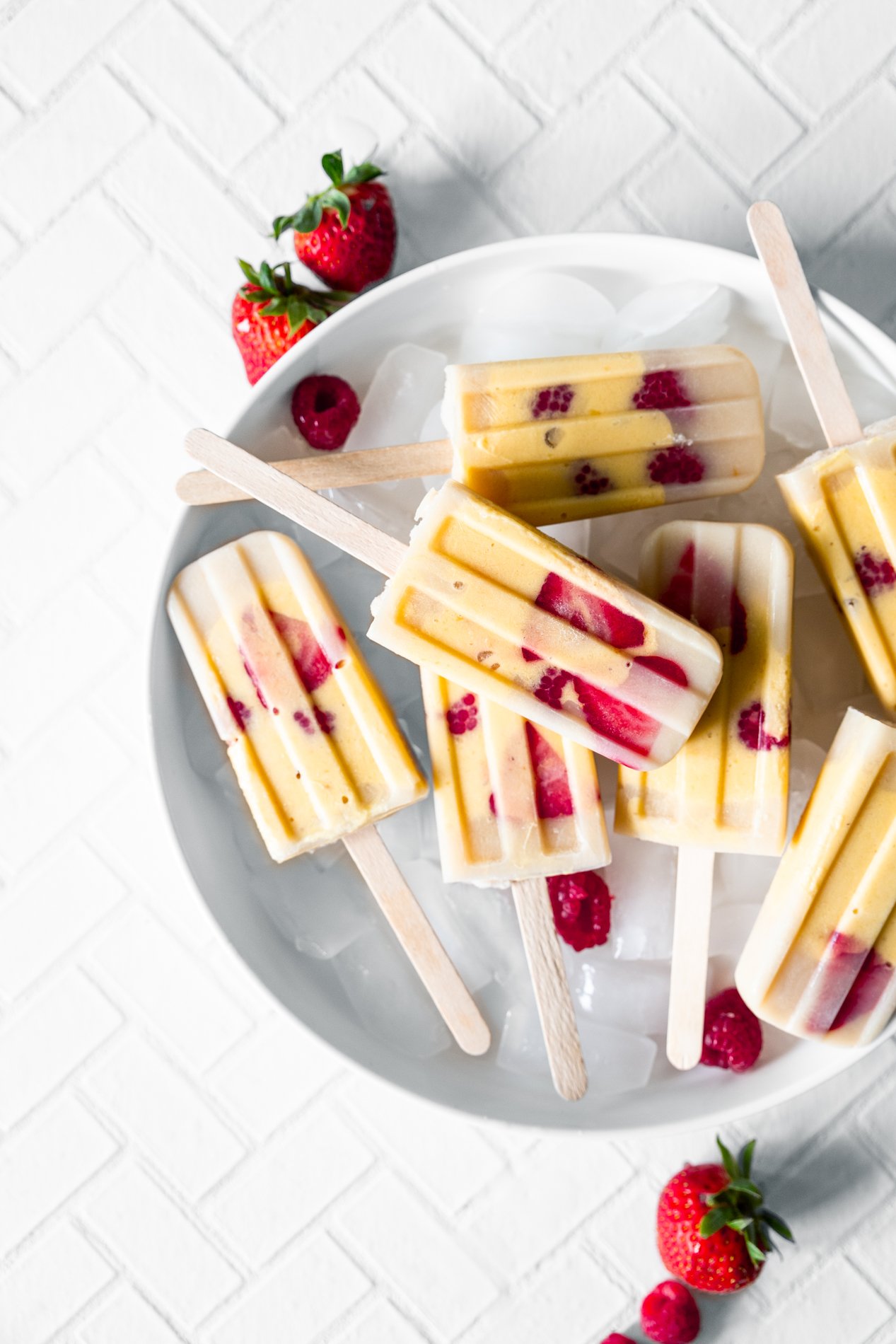overhead view of sweet mango popsicles in a dish with ice cubes