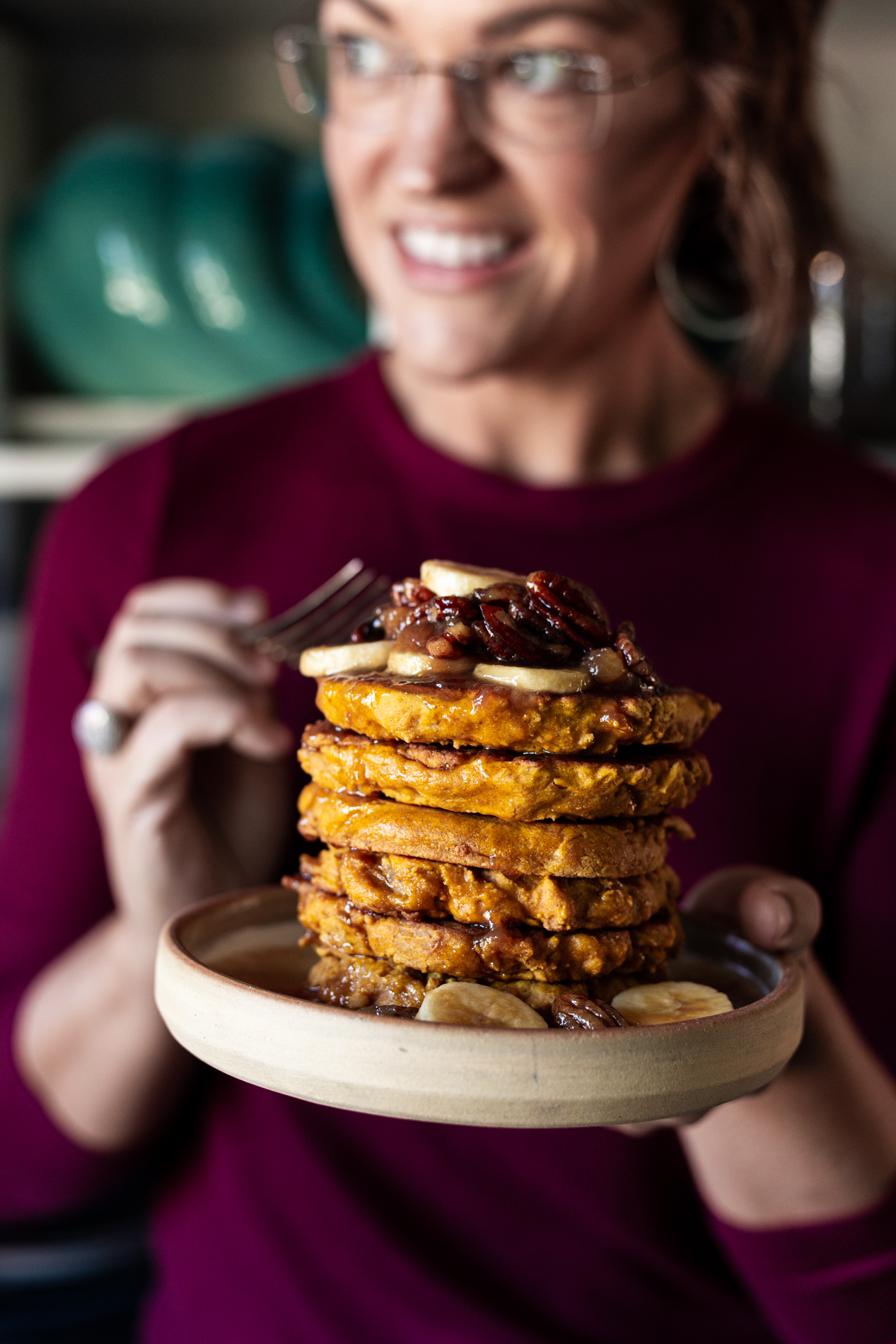 karly with a stack of pumpkin bread griddle cakes topped with caramelized bananas and pecans