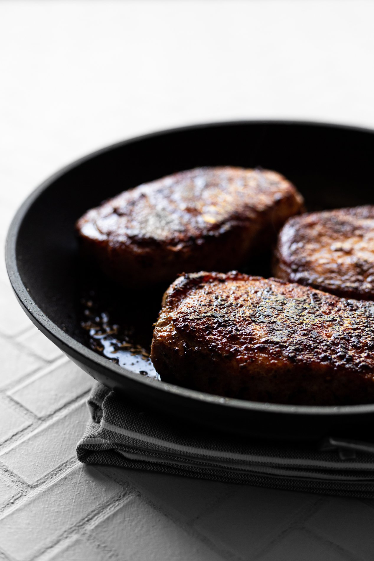 skillet with thick-cut pork chops after searing and cooking to 145 degrees