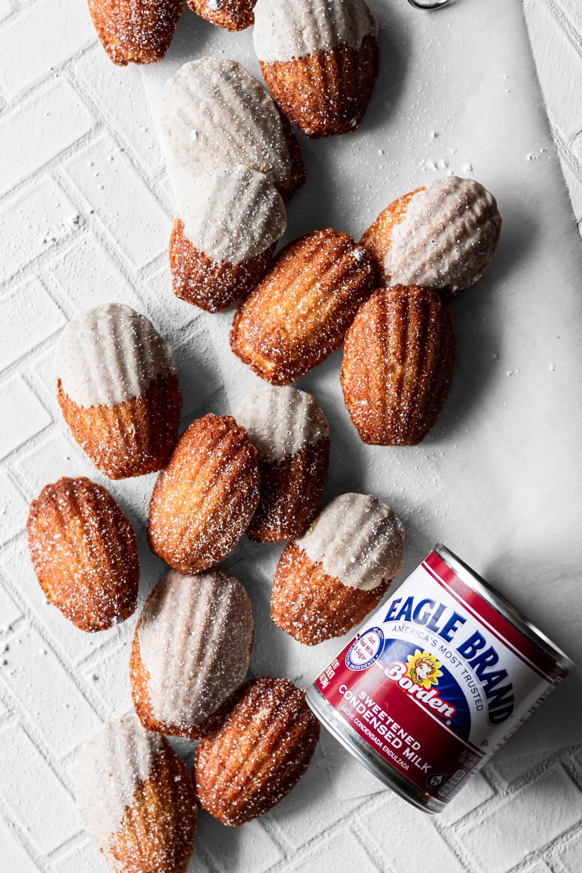 an array of vanilla bean madeleines with a can of sweetened condensed milk