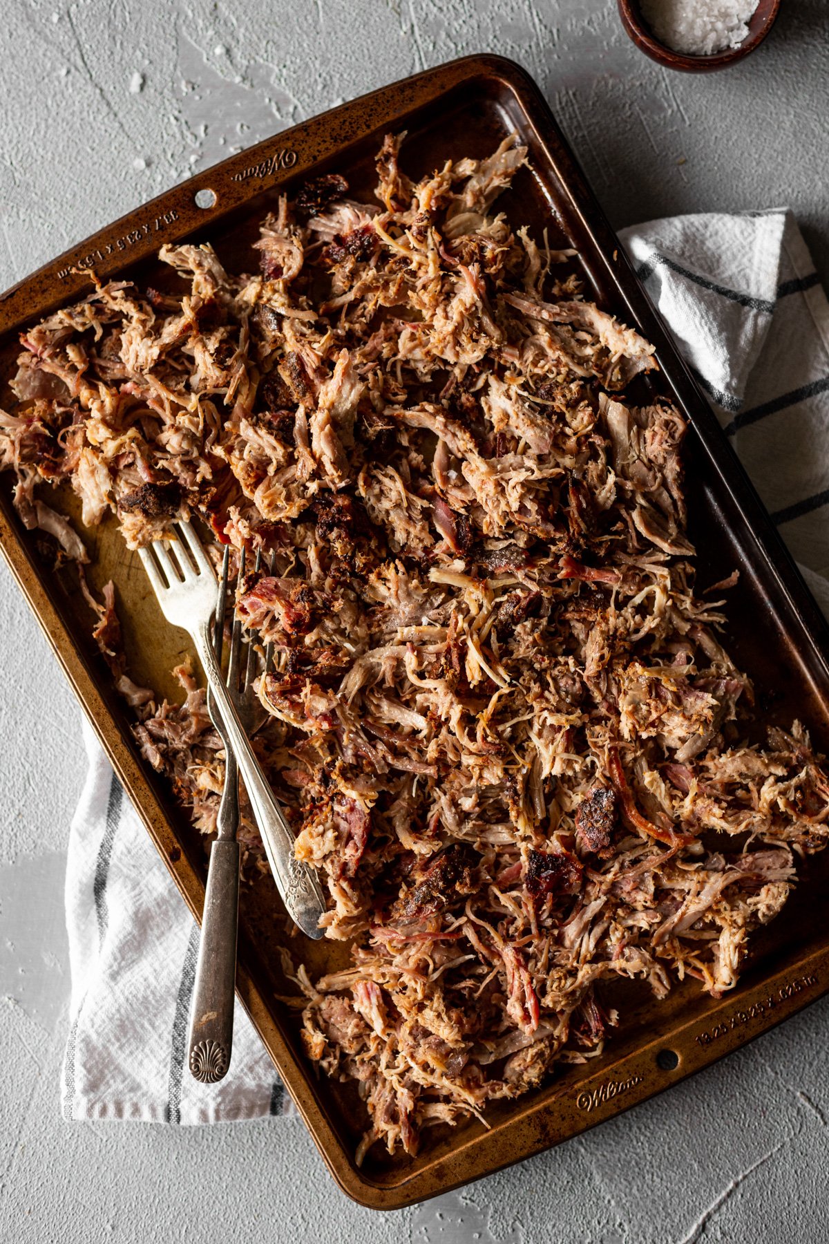 smoked pulled pork on a metal sheet pan with forks