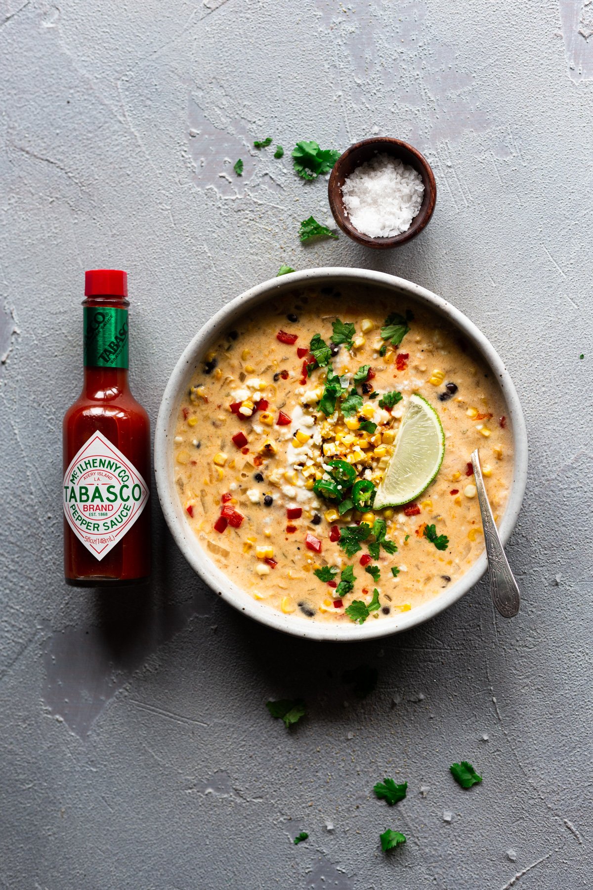 bowl of easy mexican street corn chowder with garnishes and a bottle of TABASCO® Sauce