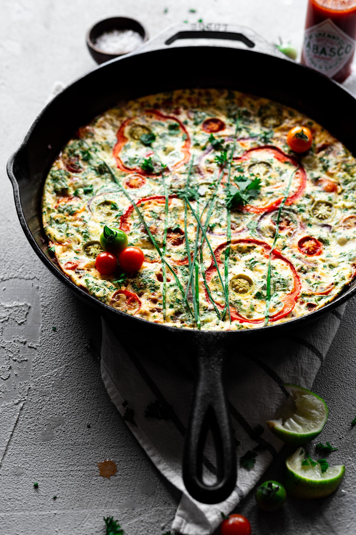 angled view of baked frittata recipe with veggies and herbs