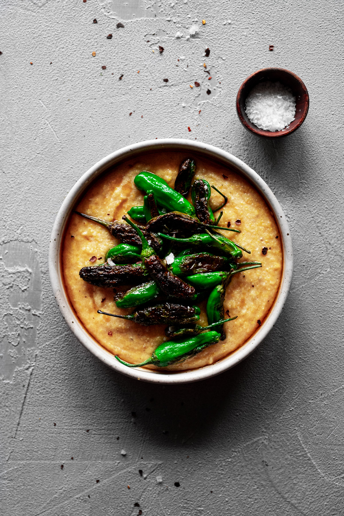 blistered shishito peppers on top of polenta with a honey-soy sauce and hot chili oil