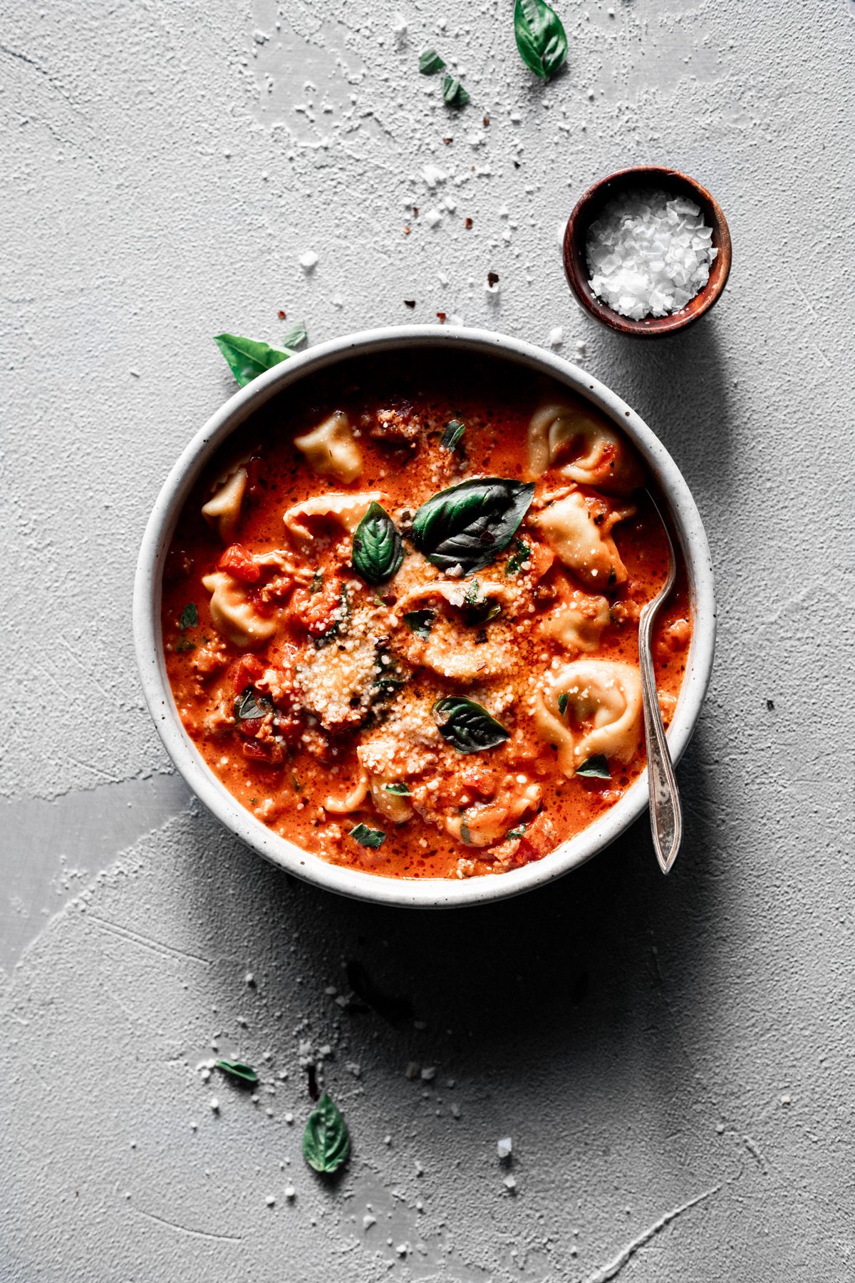 easy tortellini soup recipe in a bowl with fresh basil and parmesan with spoon