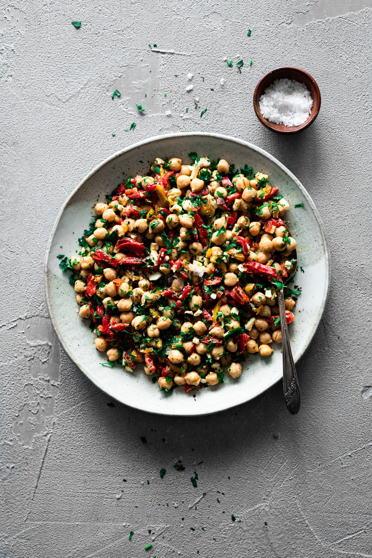 platter with Mediterranean chickpea salad recipe with a spoon and bowl of flaky sea salt